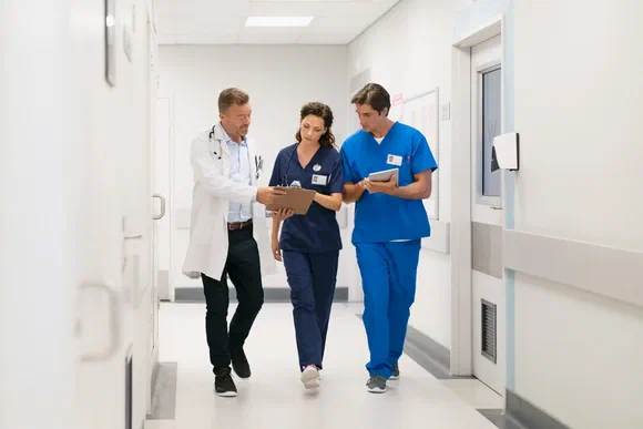 Ärztin und Pflegekräfte im Gespräch auf dem Klinikflur