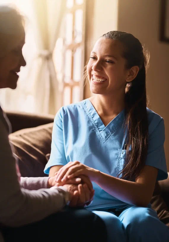 Pflegekraft hält die Hand einer Seniorin