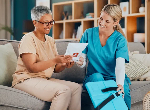 Pflegerin berät eine Seniorin bei einem Hausbesuch