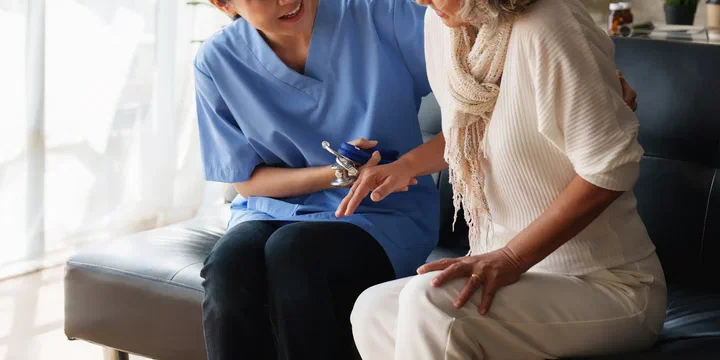 Pflegekraft hilft einer Seniorin bei Bewegungsübungen